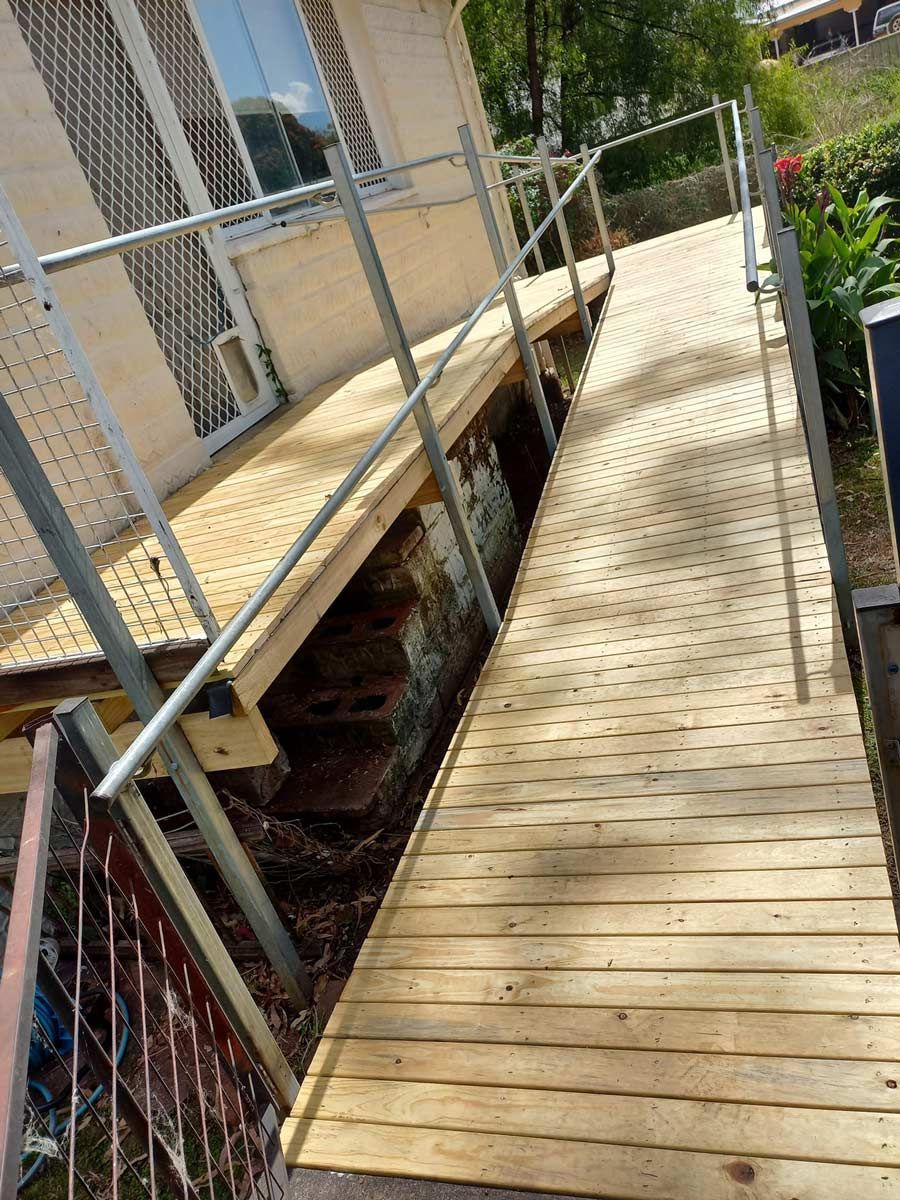 A Wooden Walkway Leading To A Building With A Metal Railing After Construction — McCarthys Property Services in Grafton, NSW