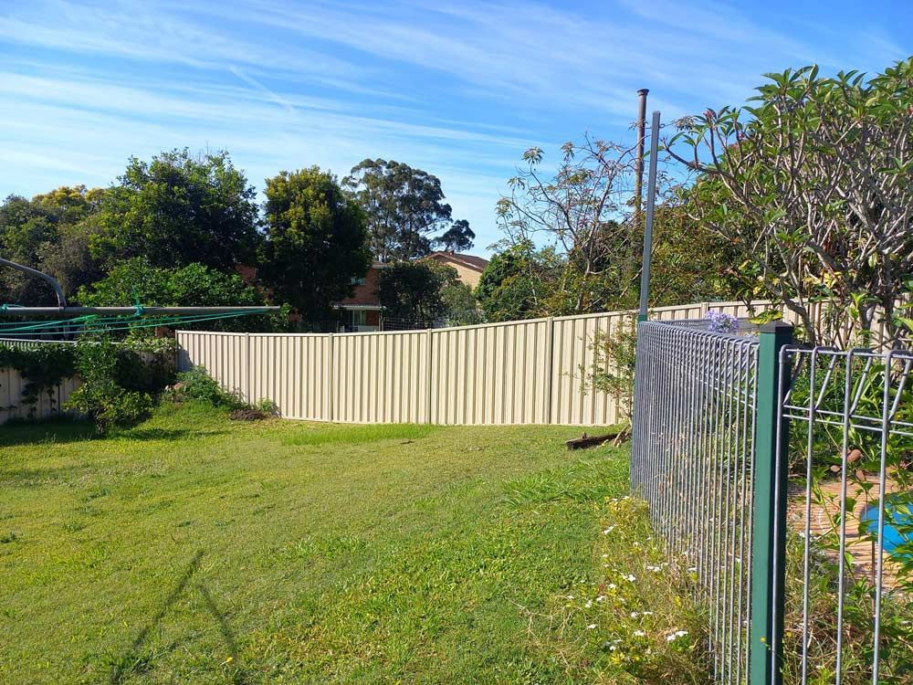 A Fence Surrounds A Lush Green Field — McCarthys Property Services in Yamba, NSW