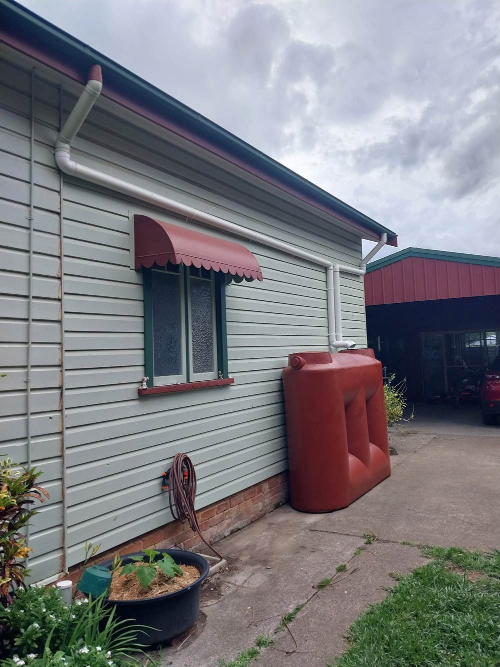 A House With A Red Water Tank In Front Of It — McCarthys Property Services in Yamba, NSW