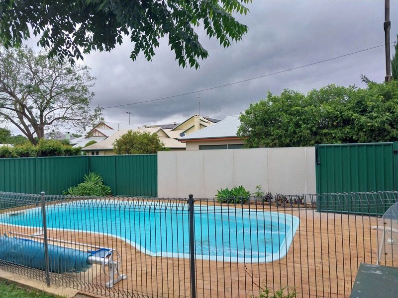 A Large Swimming Pool Surrounded By A Green Fence After — McCarthys Property Services in Glenugie, NSW