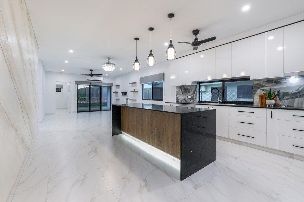 A kitchen with white cabinets and a large island in the middle.