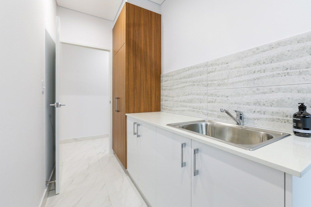 A kitchen with a sink , cabinets , and a door.