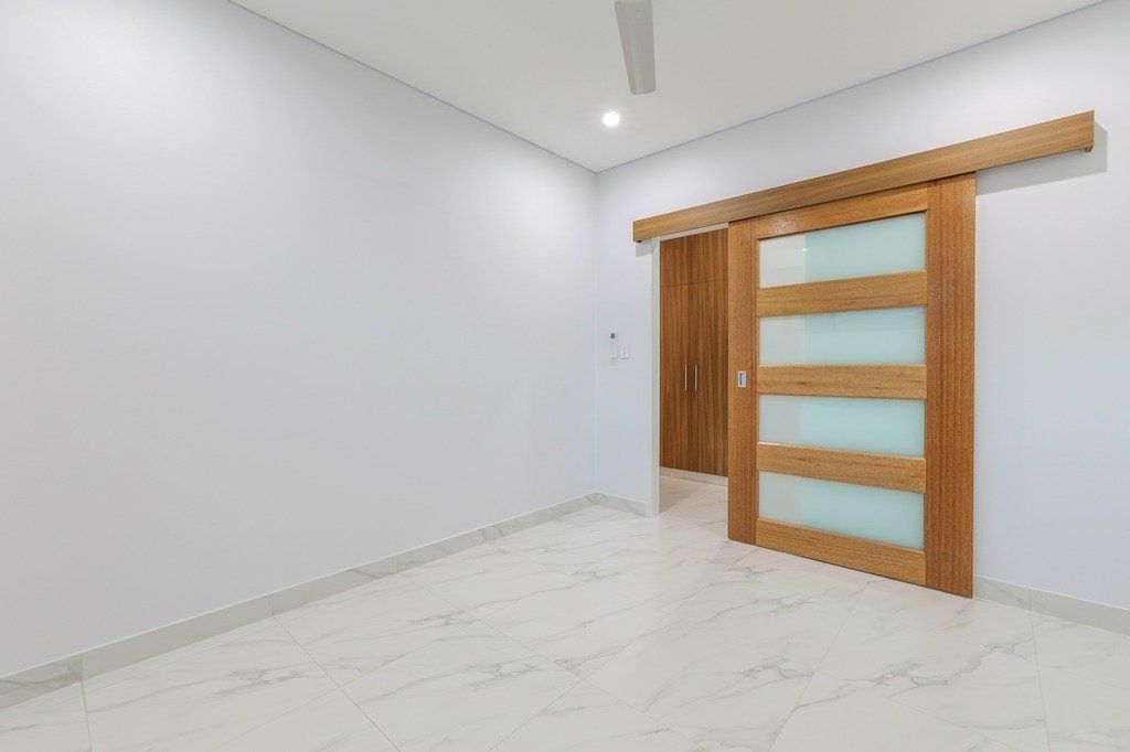 An empty room with a sliding glass door and a ceiling fan.