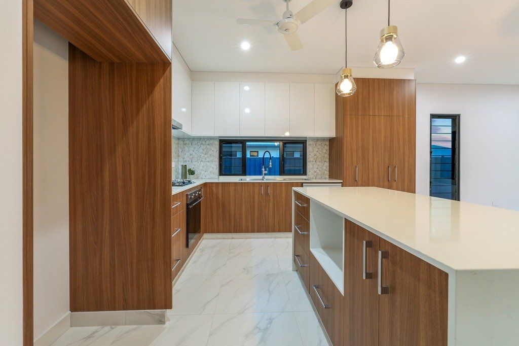 A kitchen with wooden cabinets , white counter tops , and a large island.