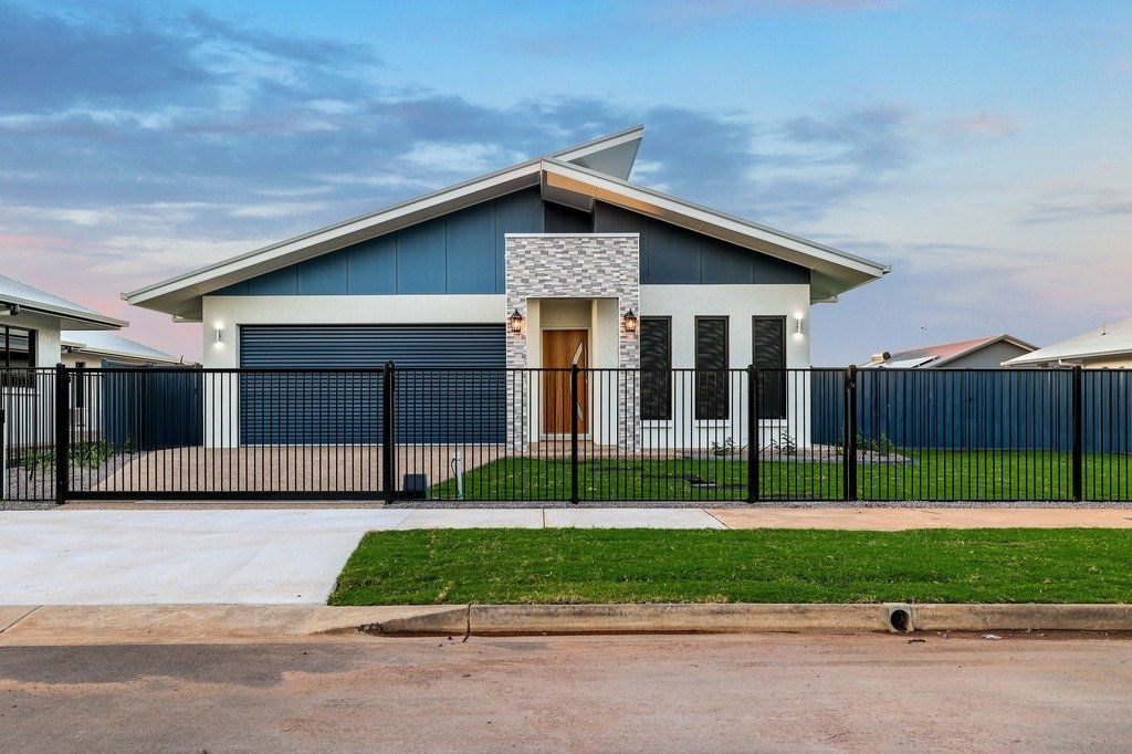 A house with a blue roof and a black fence in front of it.