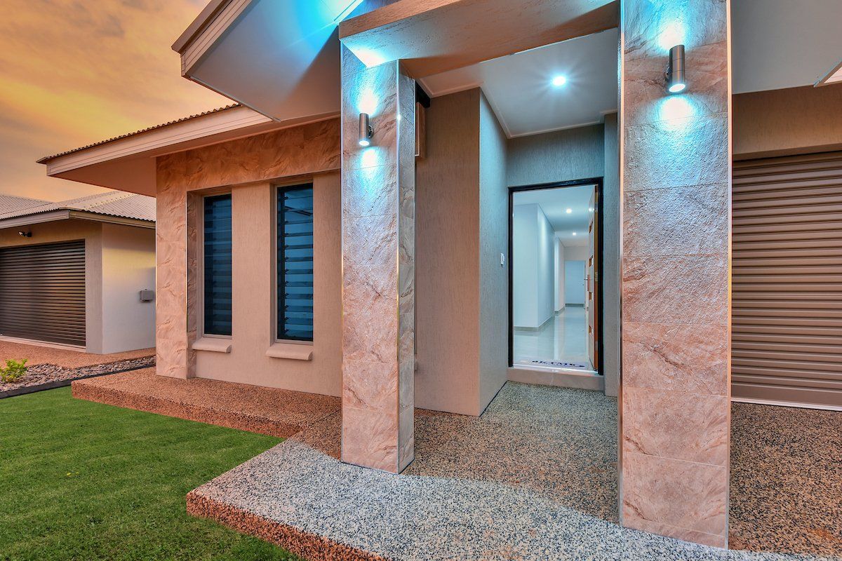 The front of a house with a lot of windows and lights on it.