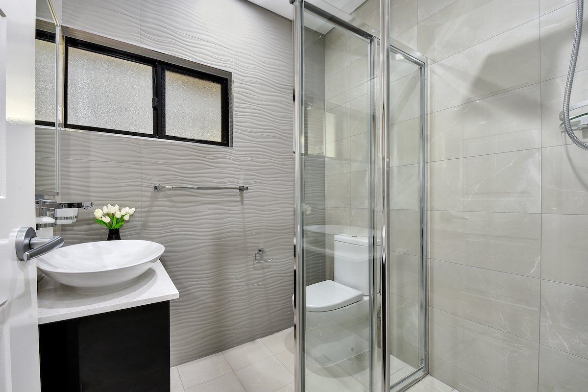 A bathroom with a toilet , sink and shower.