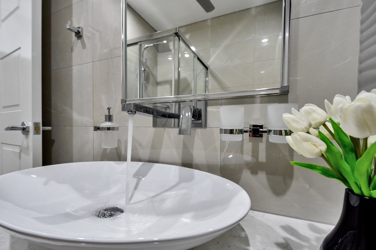 A bathroom sink with a vase of flowers next to it.