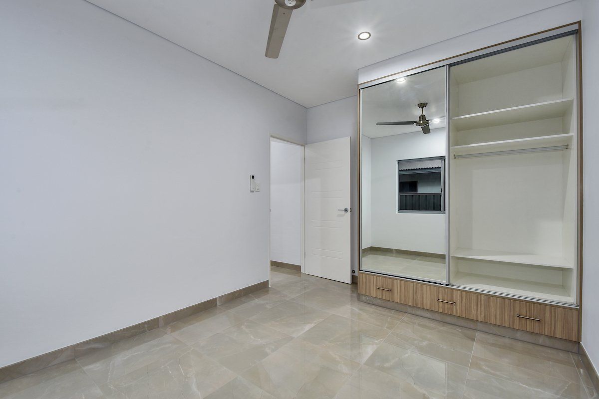 An empty room with a ceiling fan and sliding glass doors.