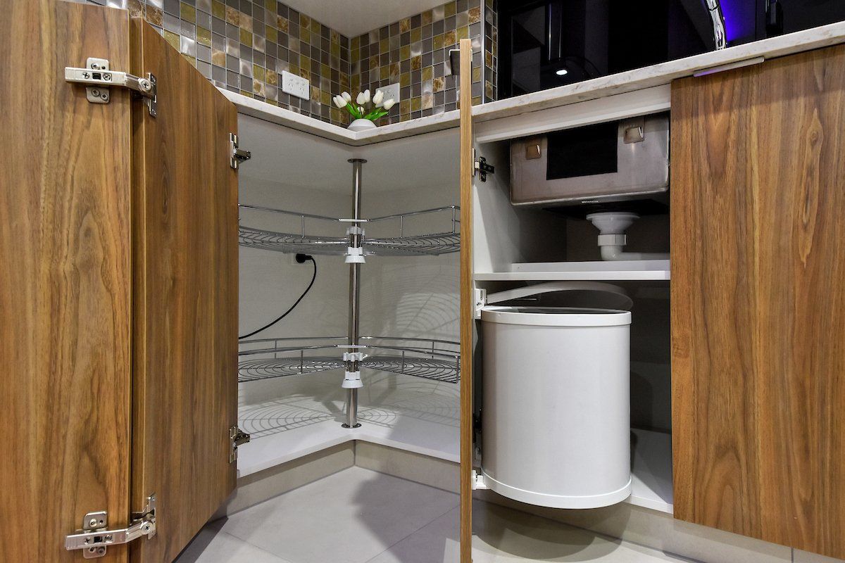 A kitchen with wooden cabinets and a white trash can under the sink.