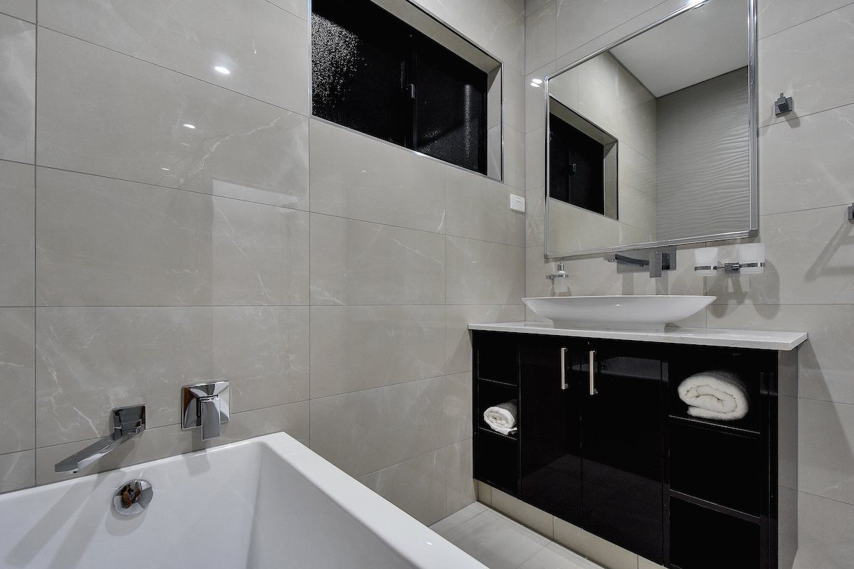 A bathroom with a bathtub , sink and mirror