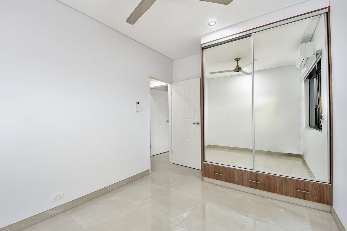 An empty bedroom with a large mirrored wardrobe and a ceiling fan.