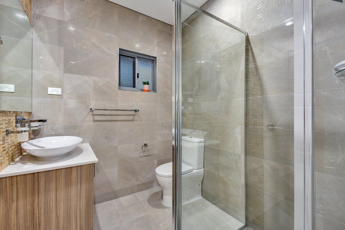 A bathroom with a toilet , sink and walk in shower.