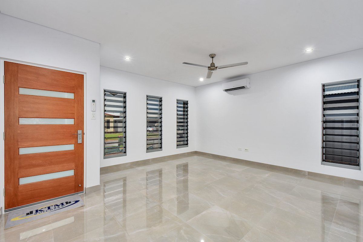 An empty living room with a wooden door and a ceiling fan.