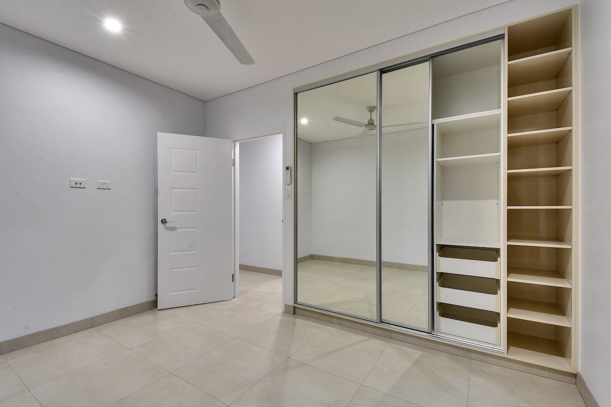 An empty bedroom with sliding glass doors and shelves.