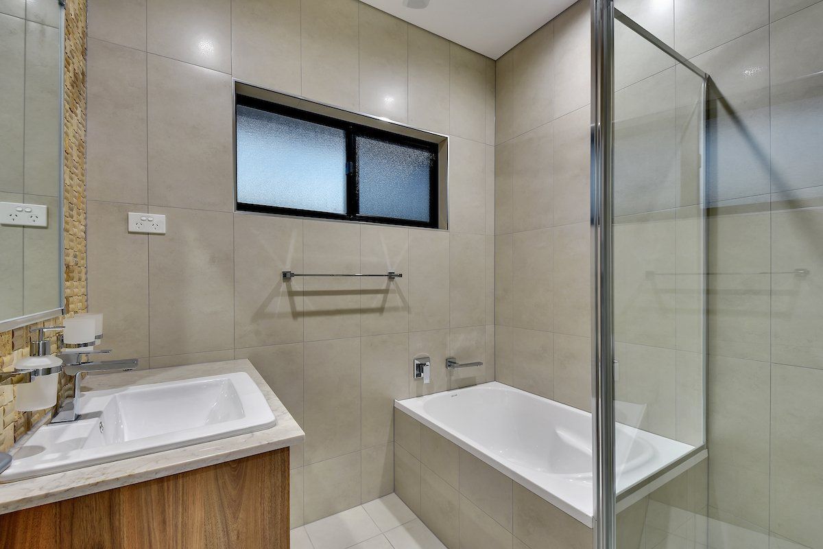 A bathroom with a tub , sink , mirror and shower.