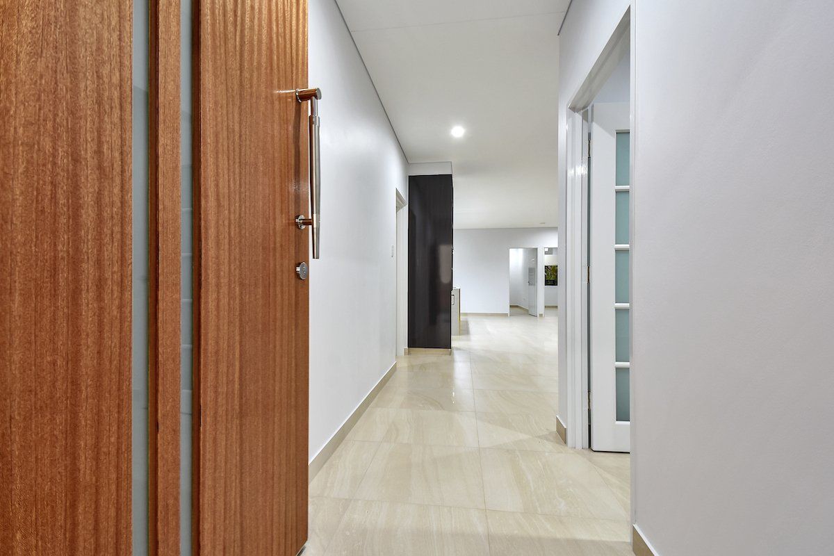 A long hallway with a wooden door and white walls.