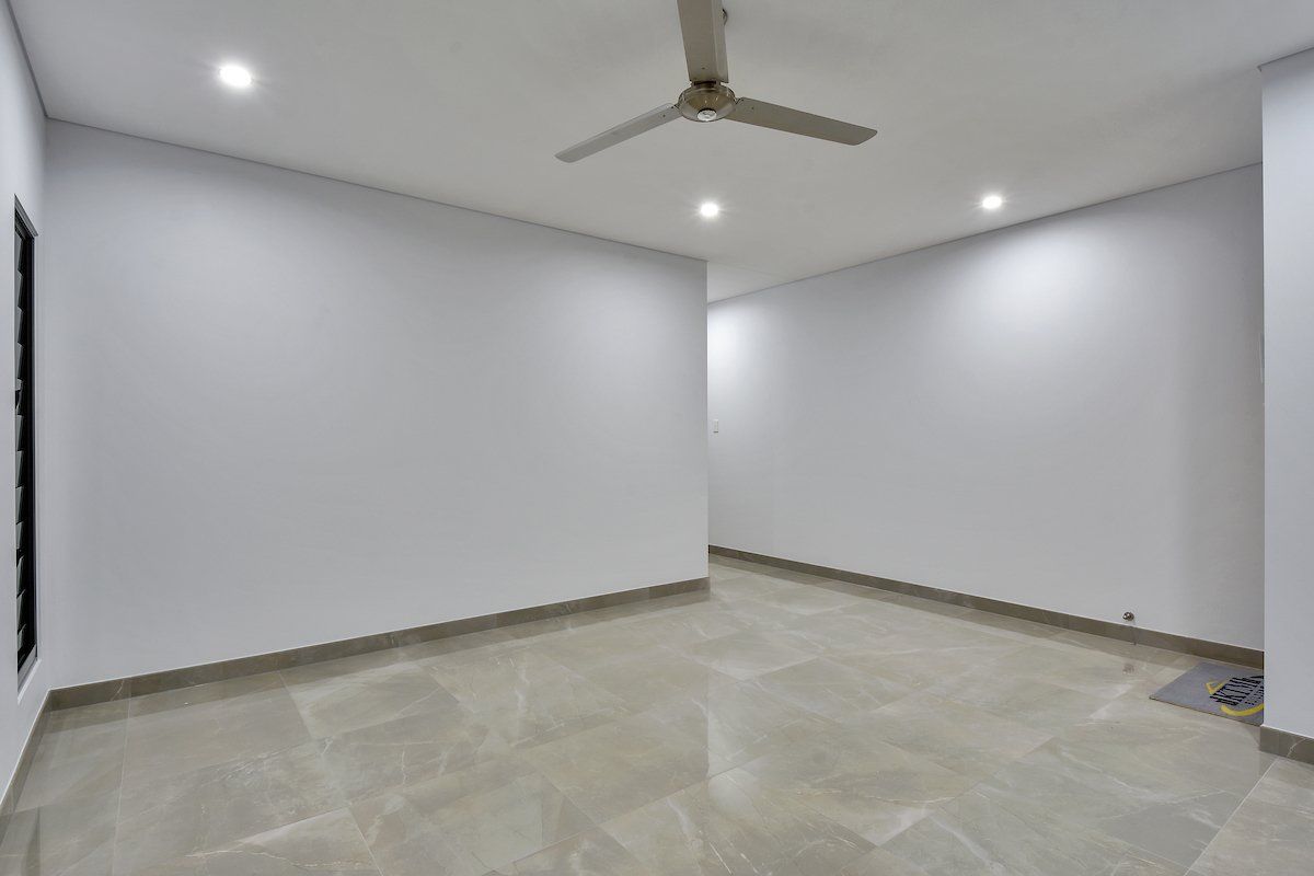 An empty room with white walls and a ceiling fan.