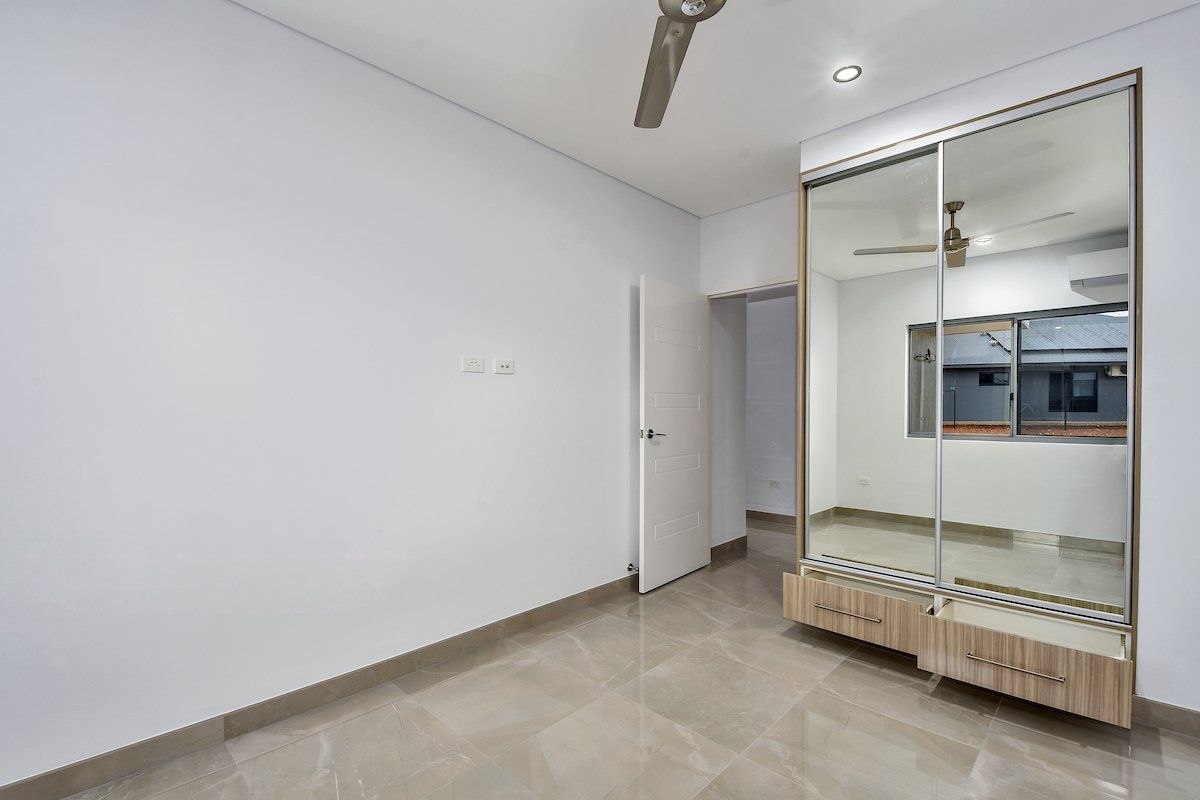 An empty room with a large mirror on the wall and a ceiling fan.
