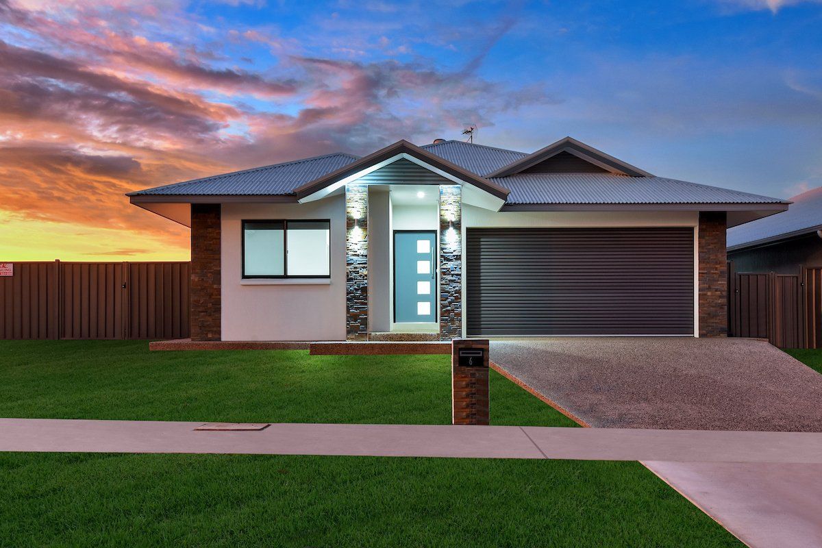 A house with a lot of grass in front of it and a sunset in the background.