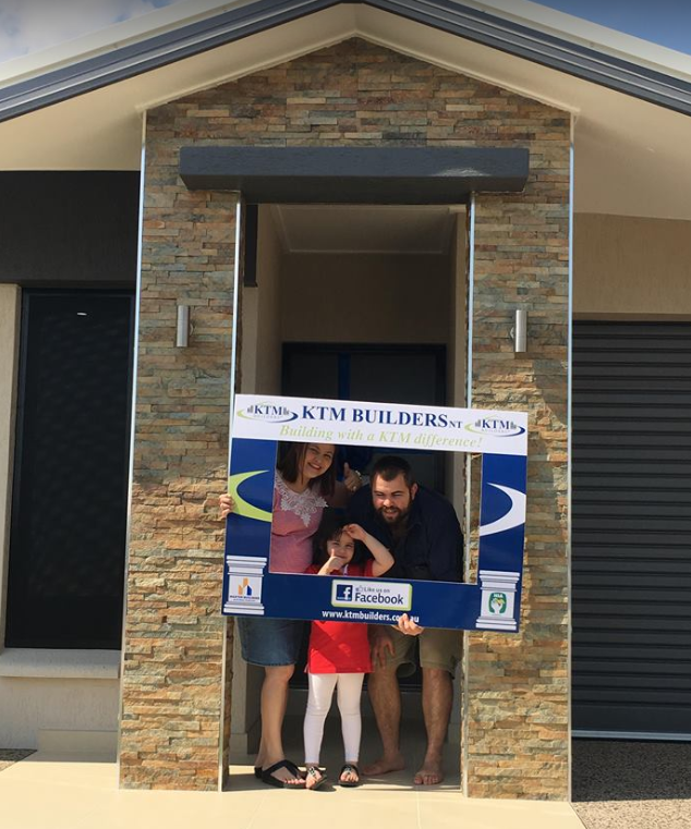 A family holding a sign that says kim builders