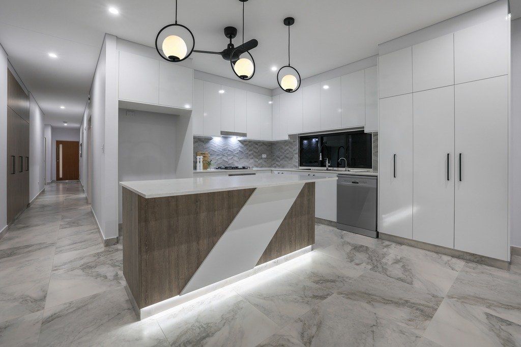 A kitchen with white cabinets , a wooden island , and a ceiling fan.