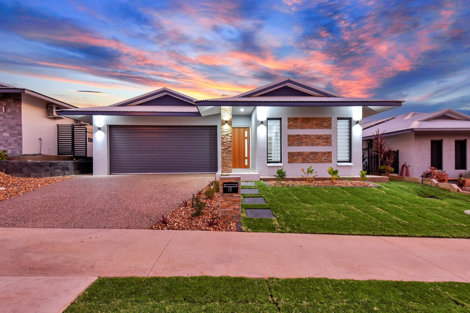 The front of a house with a large garage and a lush green lawn.