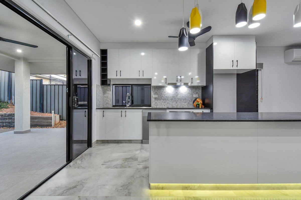 A kitchen with white cabinets and a black counter top