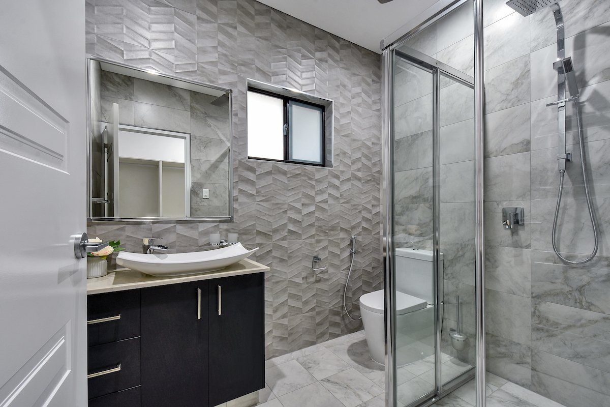 A bathroom with a sink , toilet , shower and mirror.