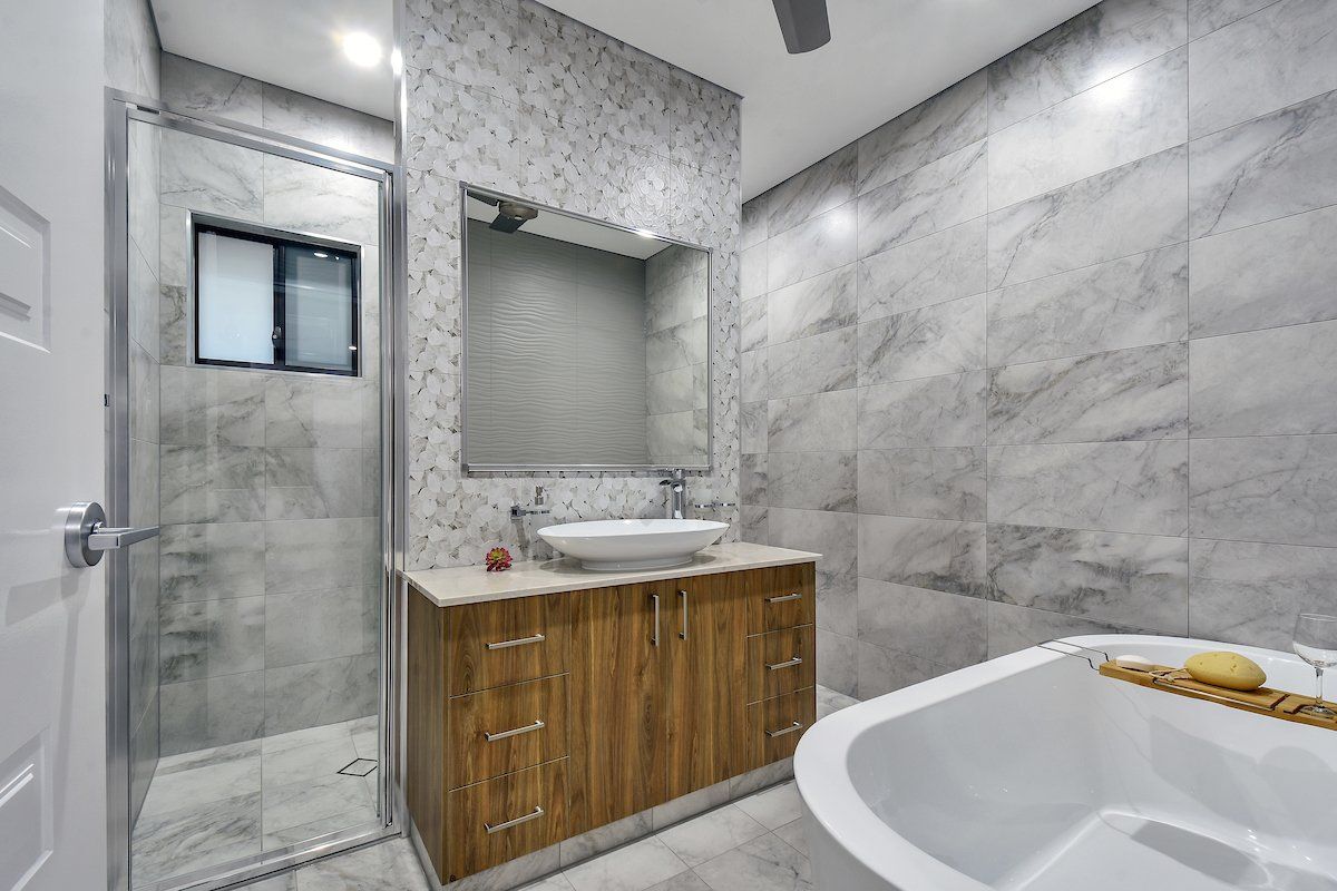 A bathroom with a sink , tub , shower and mirror.