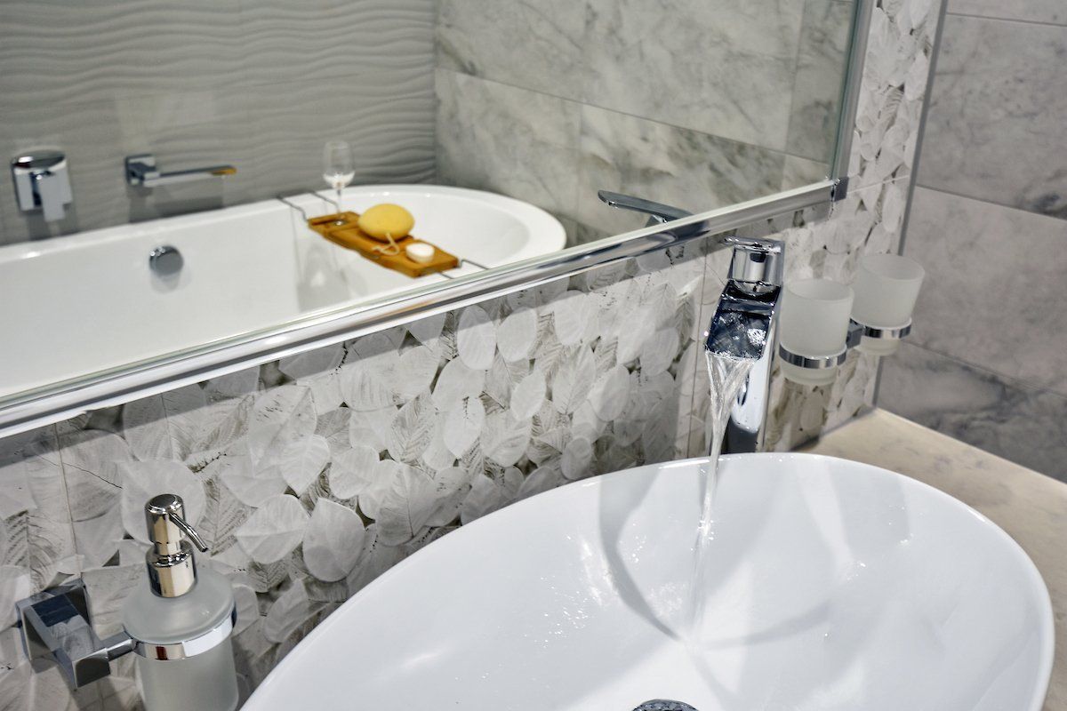 A bathroom with a sink , bathtub and mirror.