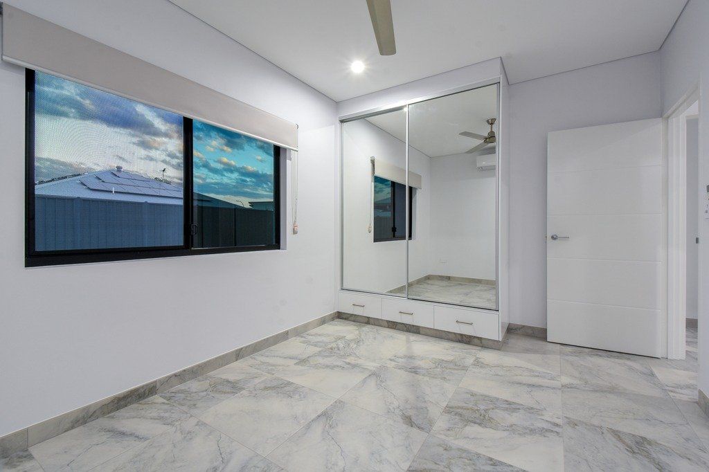 An empty bedroom with a large mirrored wardrobe and a ceiling fan.