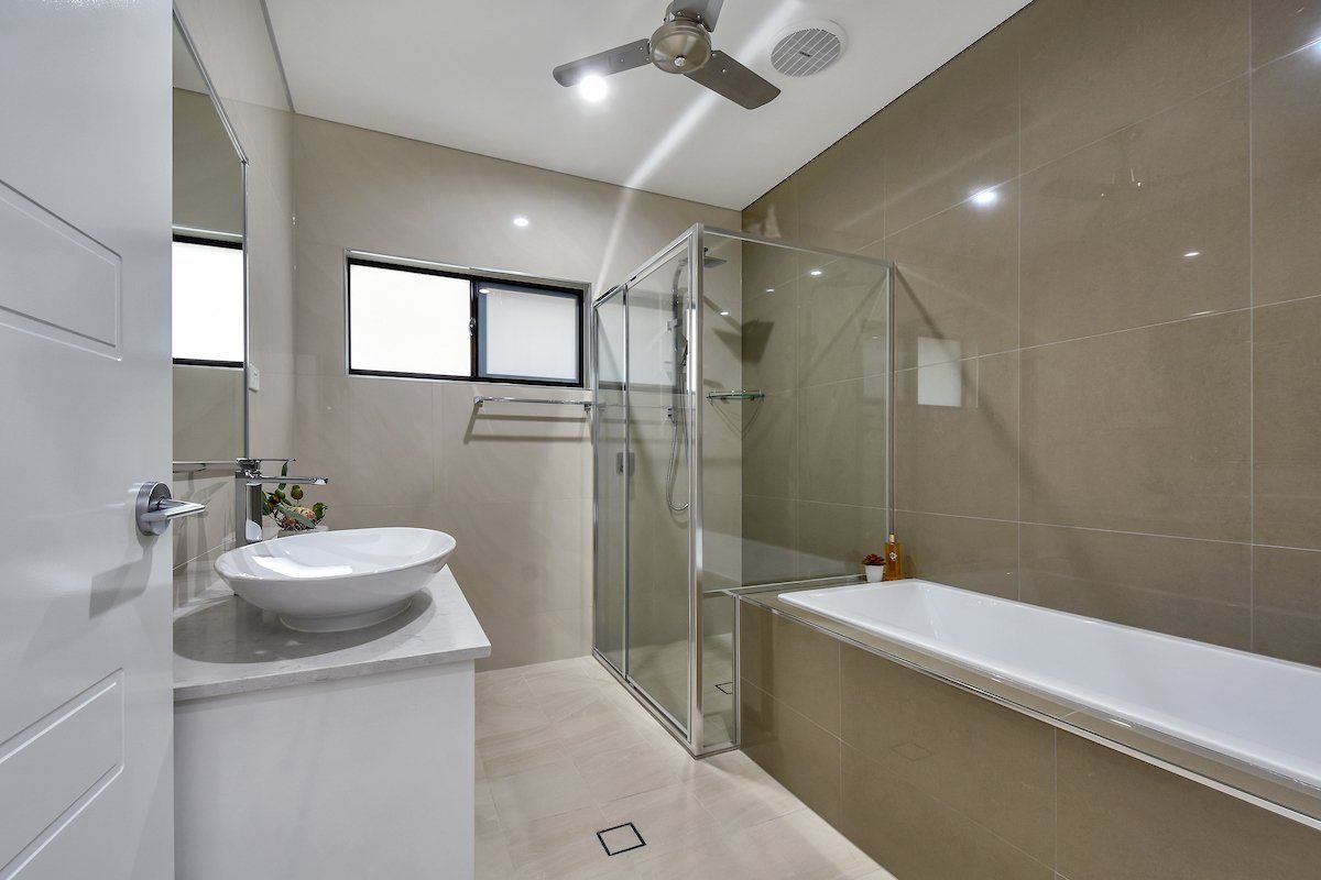 A bathroom with a sink , tub , shower and ceiling fan.