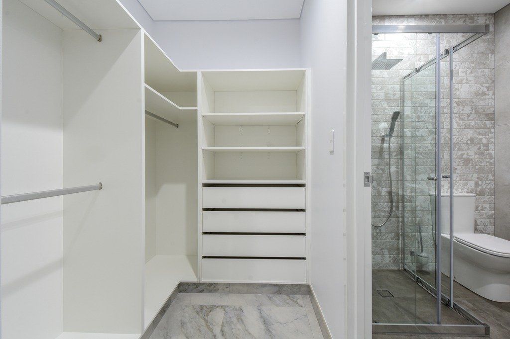 A walk in closet with a glass shower door in a bathroom.