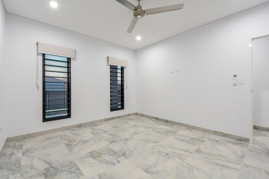 An empty room with a ceiling fan and two windows.
