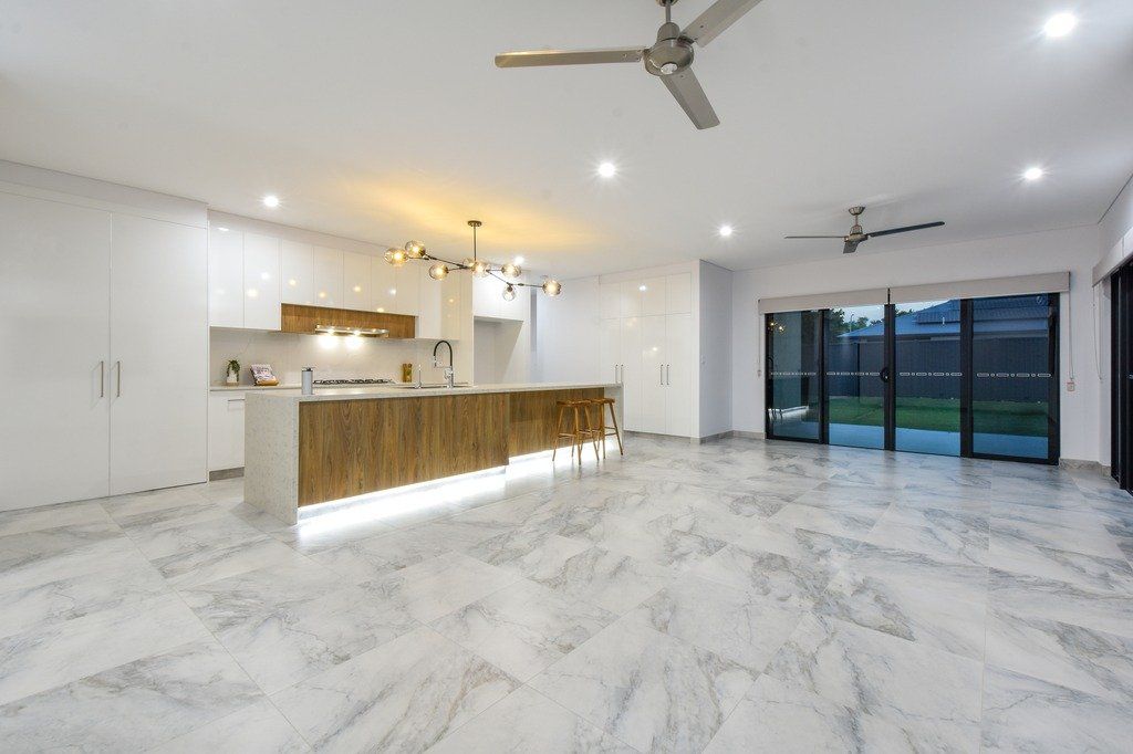 A large empty room with a ceiling fan and marble floors.