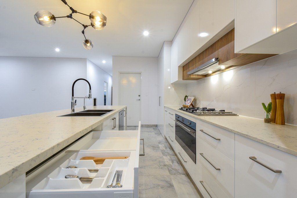 A kitchen with white cabinets , a stove and a sink