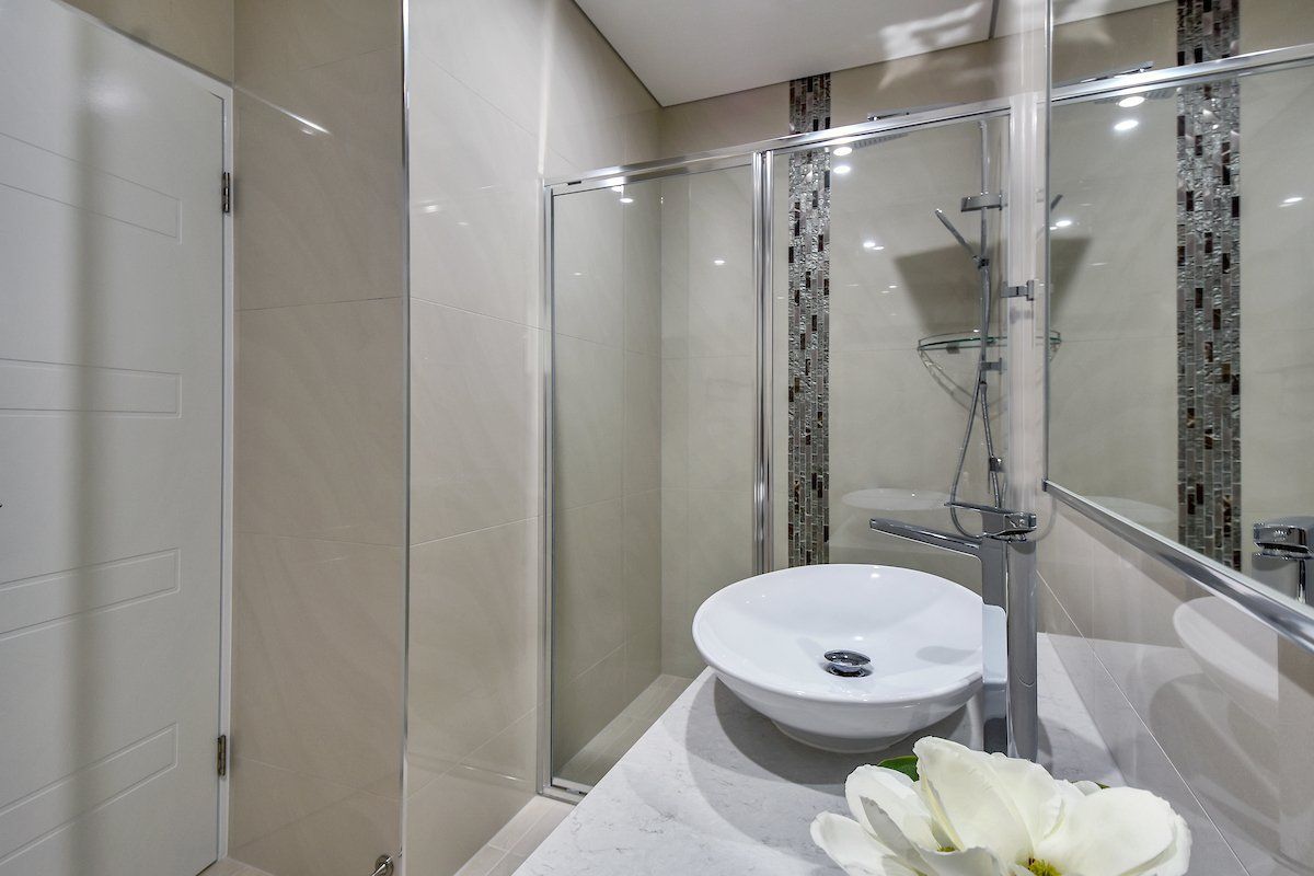 A bathroom with a sink , mirror and shower stall.