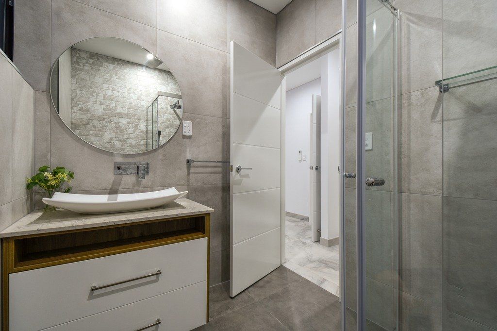 A bathroom with a sink , mirror , and walk in shower.