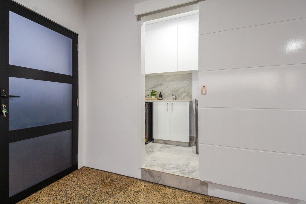 A room with a sliding glass door leading to a kitchen.