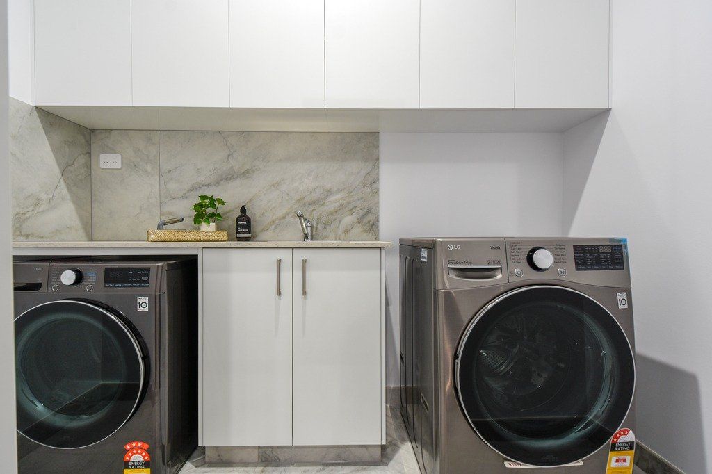 A laundry room with two washing machines and a dryer.