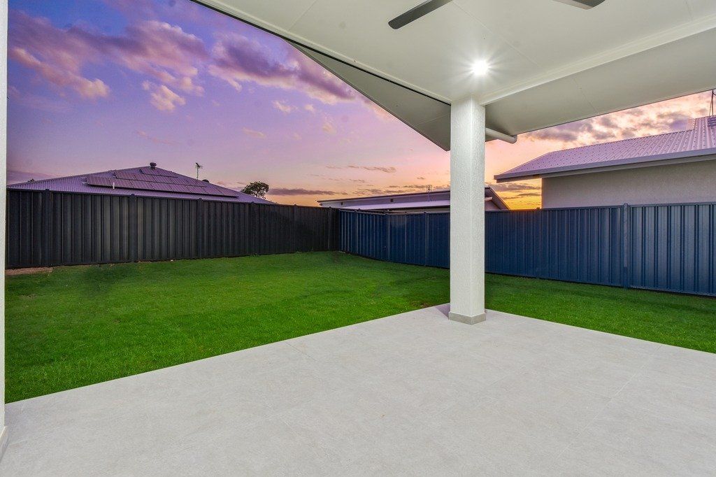 An empty patio with a ceiling fan and a fence in the background.