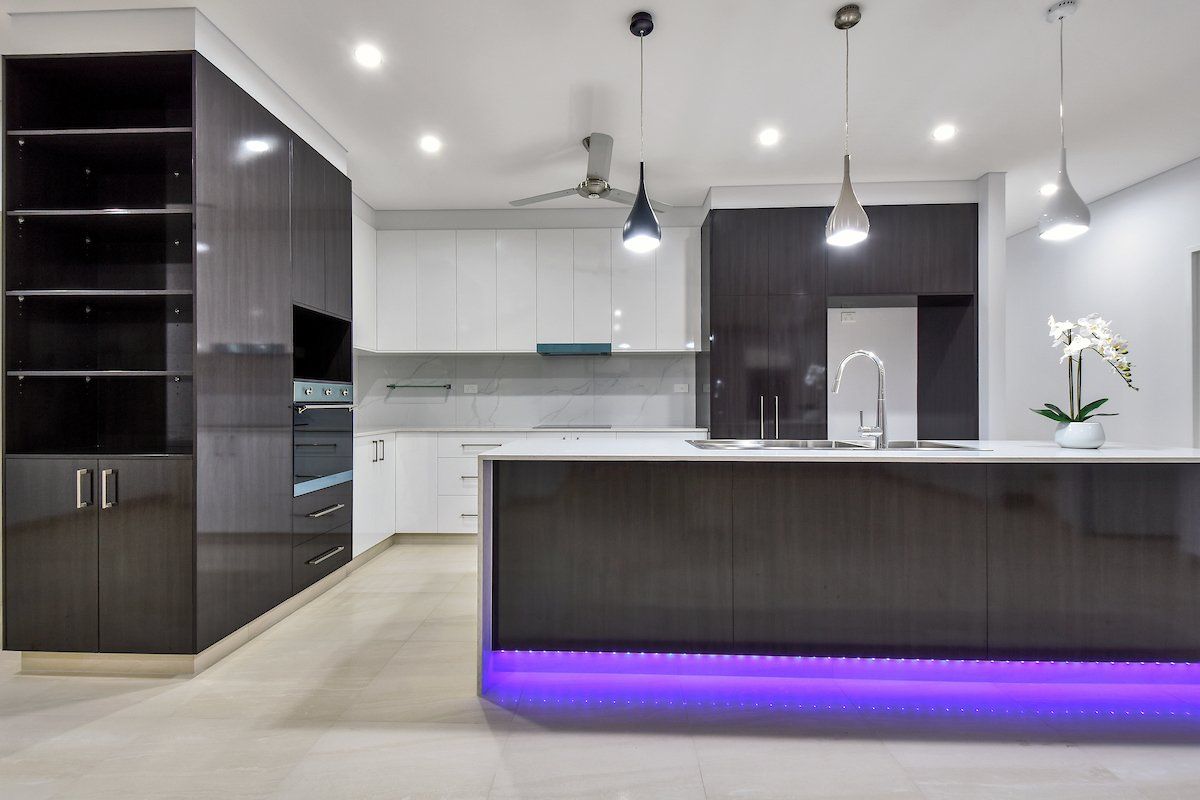 A kitchen with black and white cabinets and purple lights