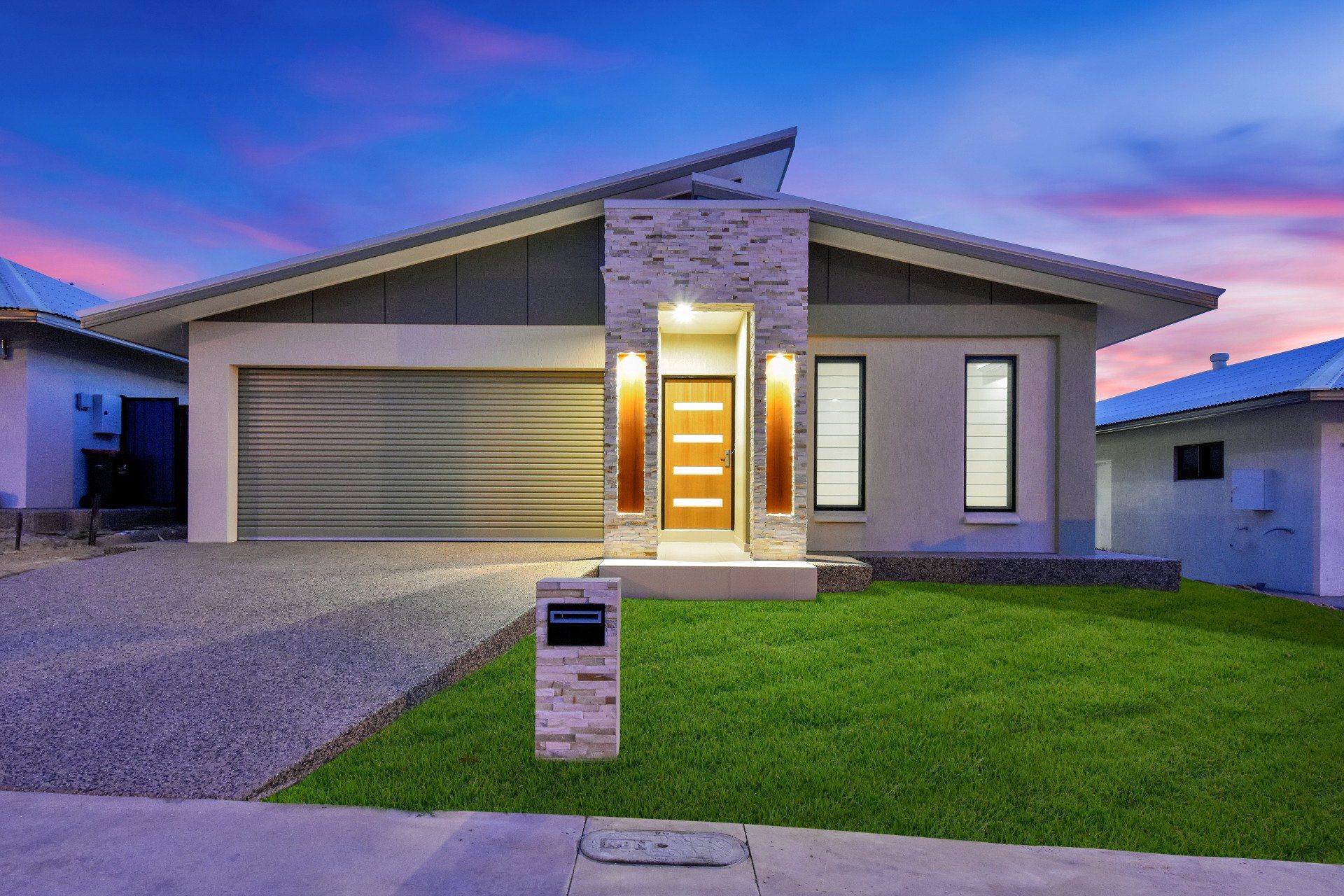 A modern house with a large garage and a lush green lawn.