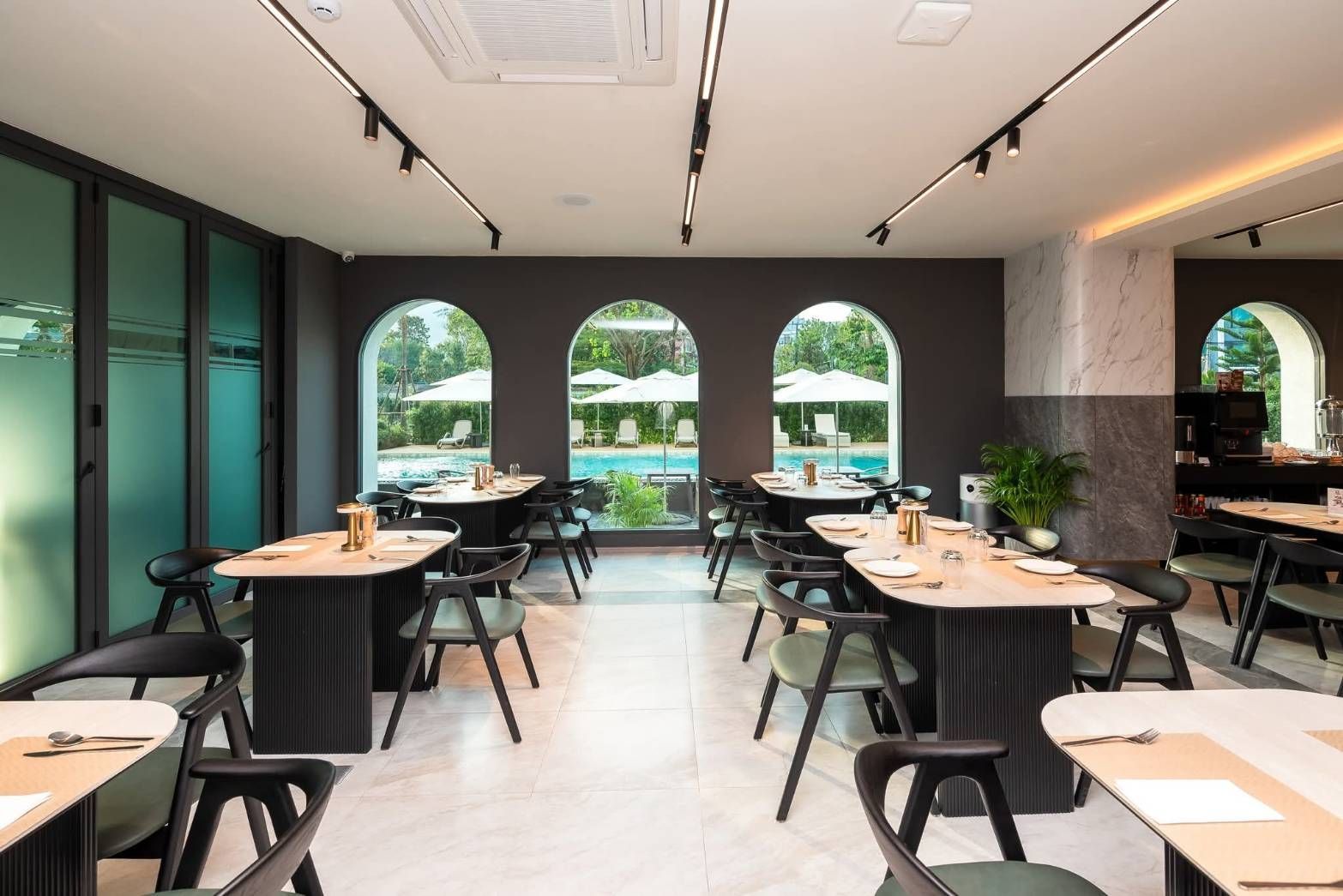 Modern café dining room with black chairs, light wood tables, and arched windows
