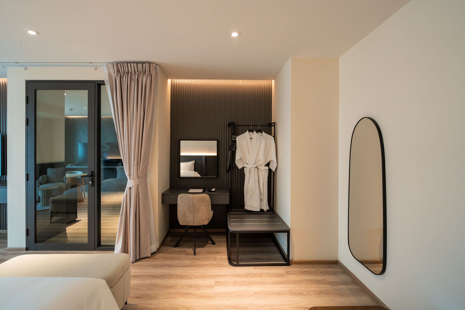 Modern bedroom with open closet, warm lighting, sliding glass doors, and a wall mirror