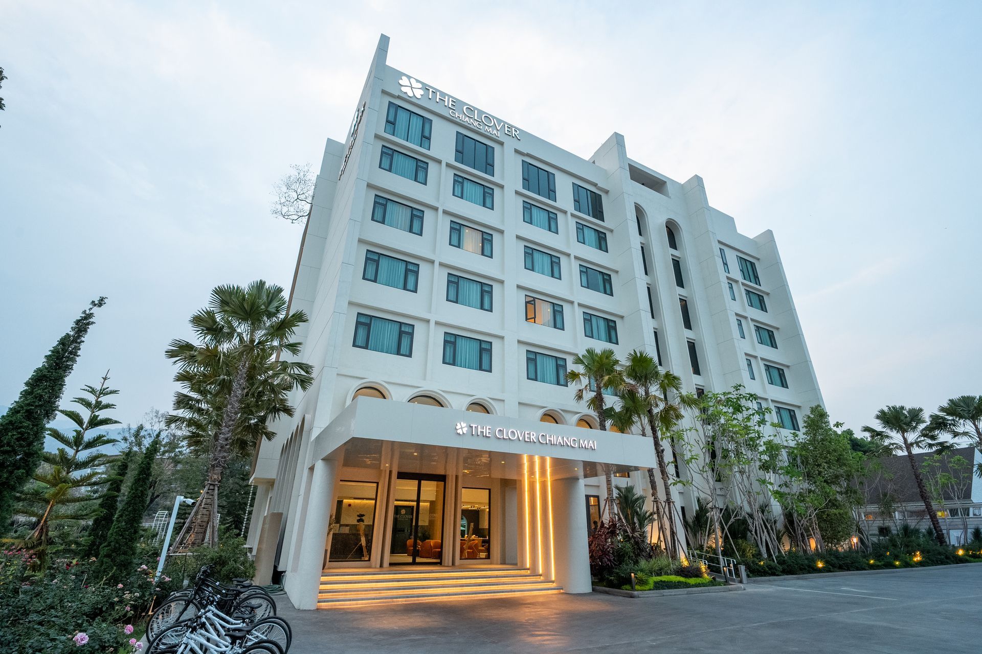 Modern white hotel building with illuminated entrance at dusk