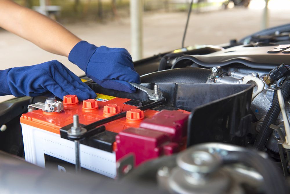 A Person Is Working On A Car Battery With A Wrench — Goodyear Autocare Bowen in Bowen, QLD
