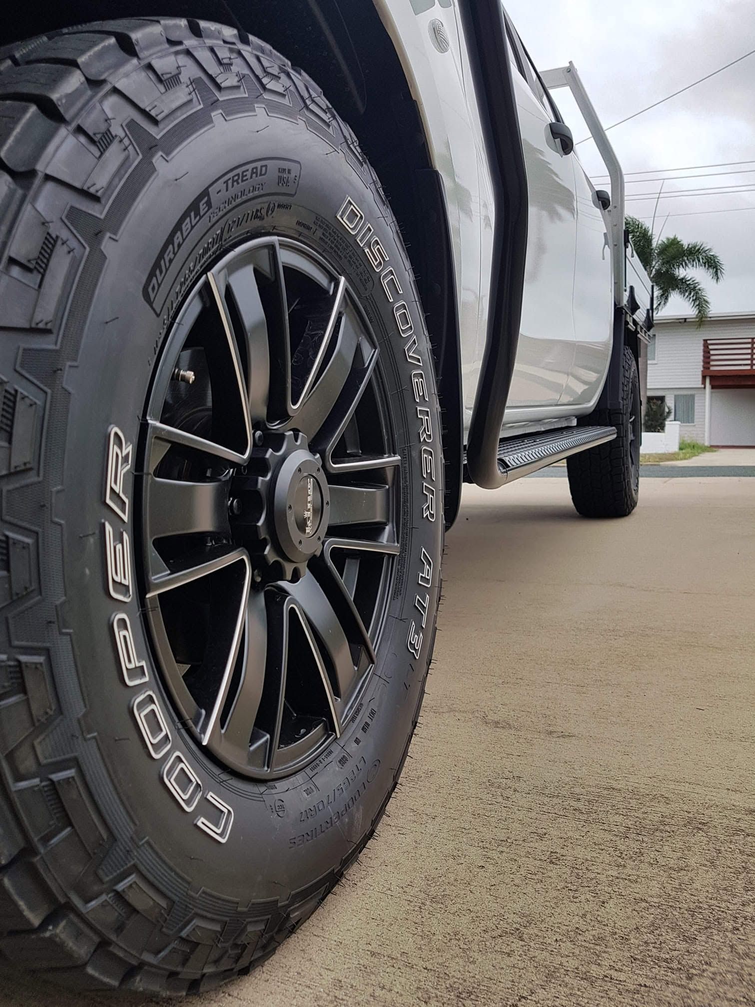 Close-up of a Black Off-road Truck Tire and Wheel on a Wet Driveway Outside a House — Goodyear Autocare Bowen in Bowen, QLD