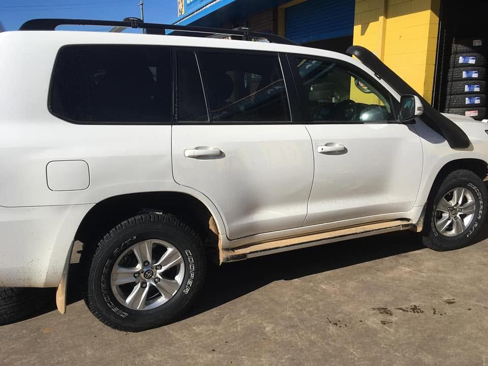 White SUV Parked Beside a Yellow Building with Muddy Lower Panel — Goodyear Autocare Bowen in Bowen, QLD